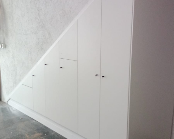 Vestidor de puertas blancas bajo una escalera. png